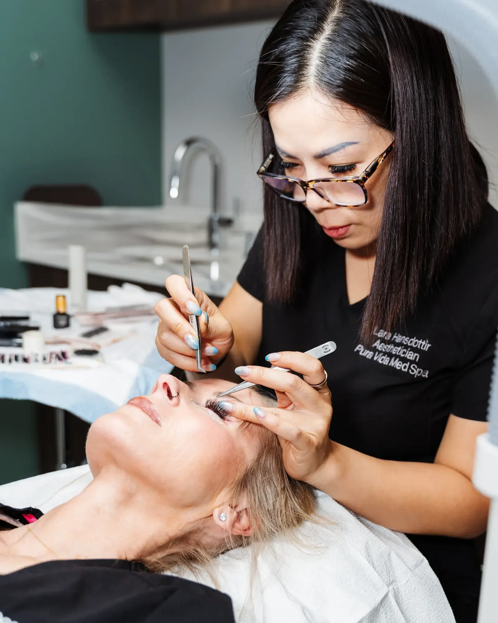 Esthetician performing a brow treatment on a reclining client at the spa