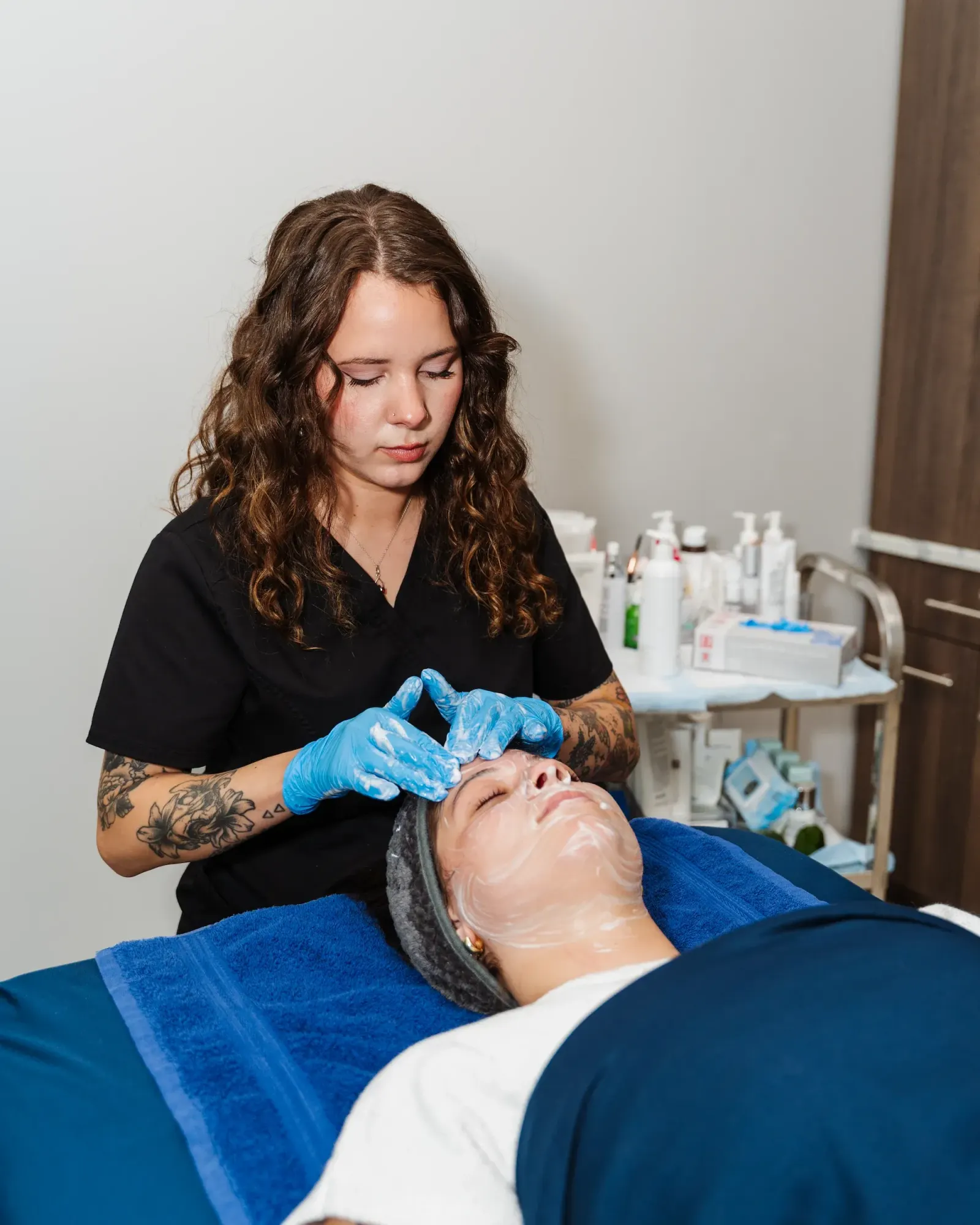 Esthetician in gloves performing a facial on a reclined client at the spa