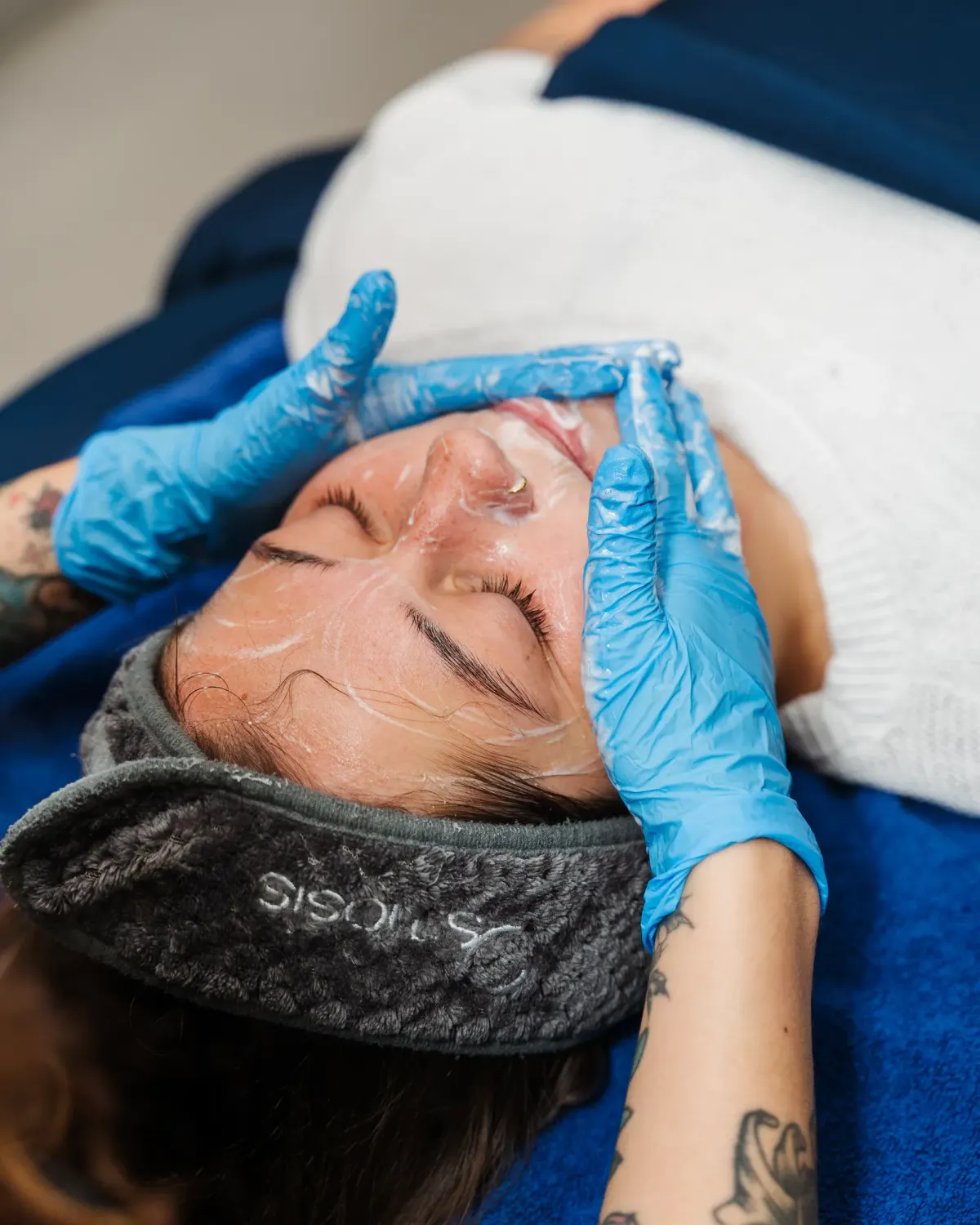 Gloved esthetician performing a facial treatment on a reclining client