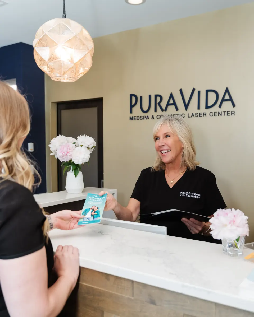 Smiling receptionist greeting a client at the Pura Vida Med Spa front desk