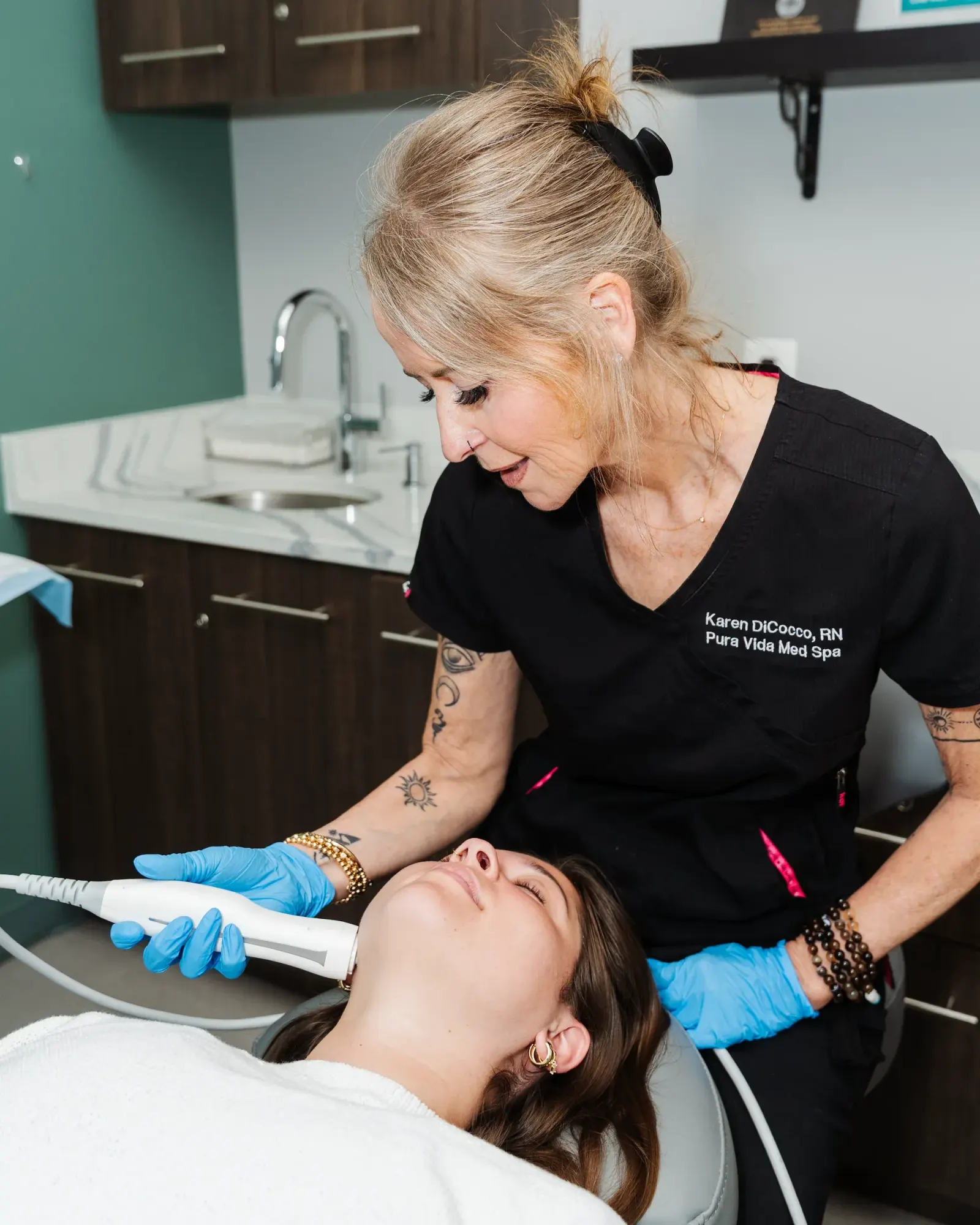 Provider using a handheld device on a reclined client's face during a treatment