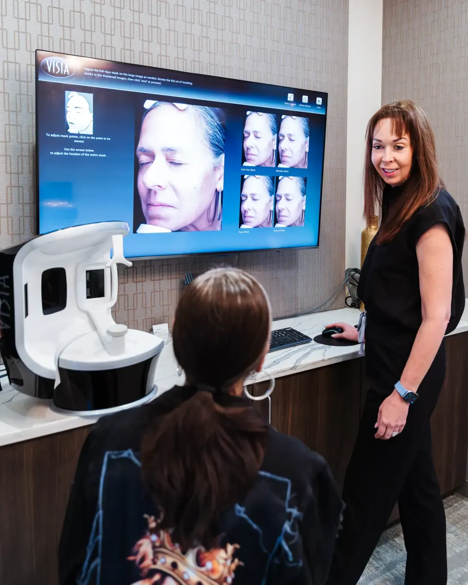Specialist performing a facial skin analysis scan on a seated client