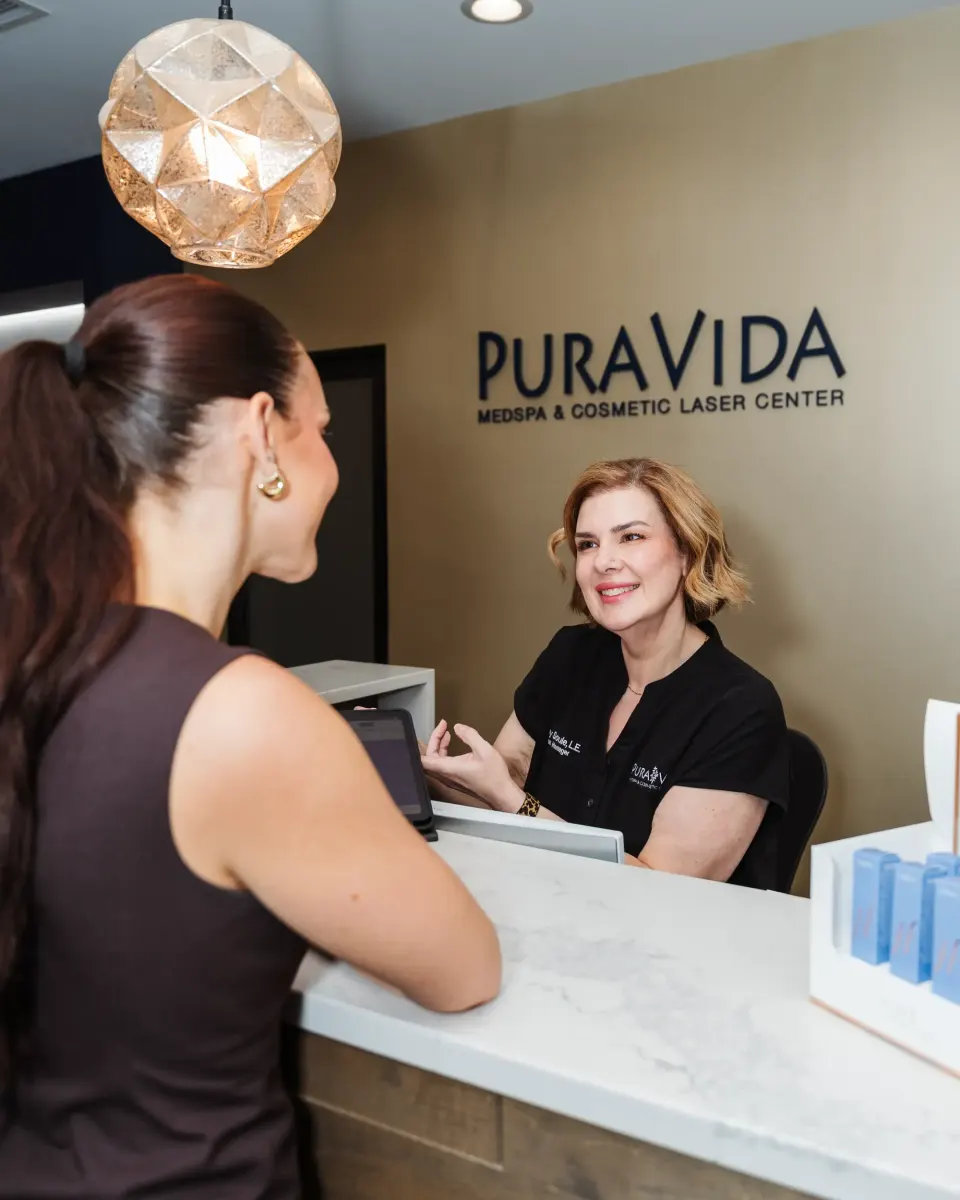 Smiling receptionist greeting a client at the Pura Vida Med Spa front desk