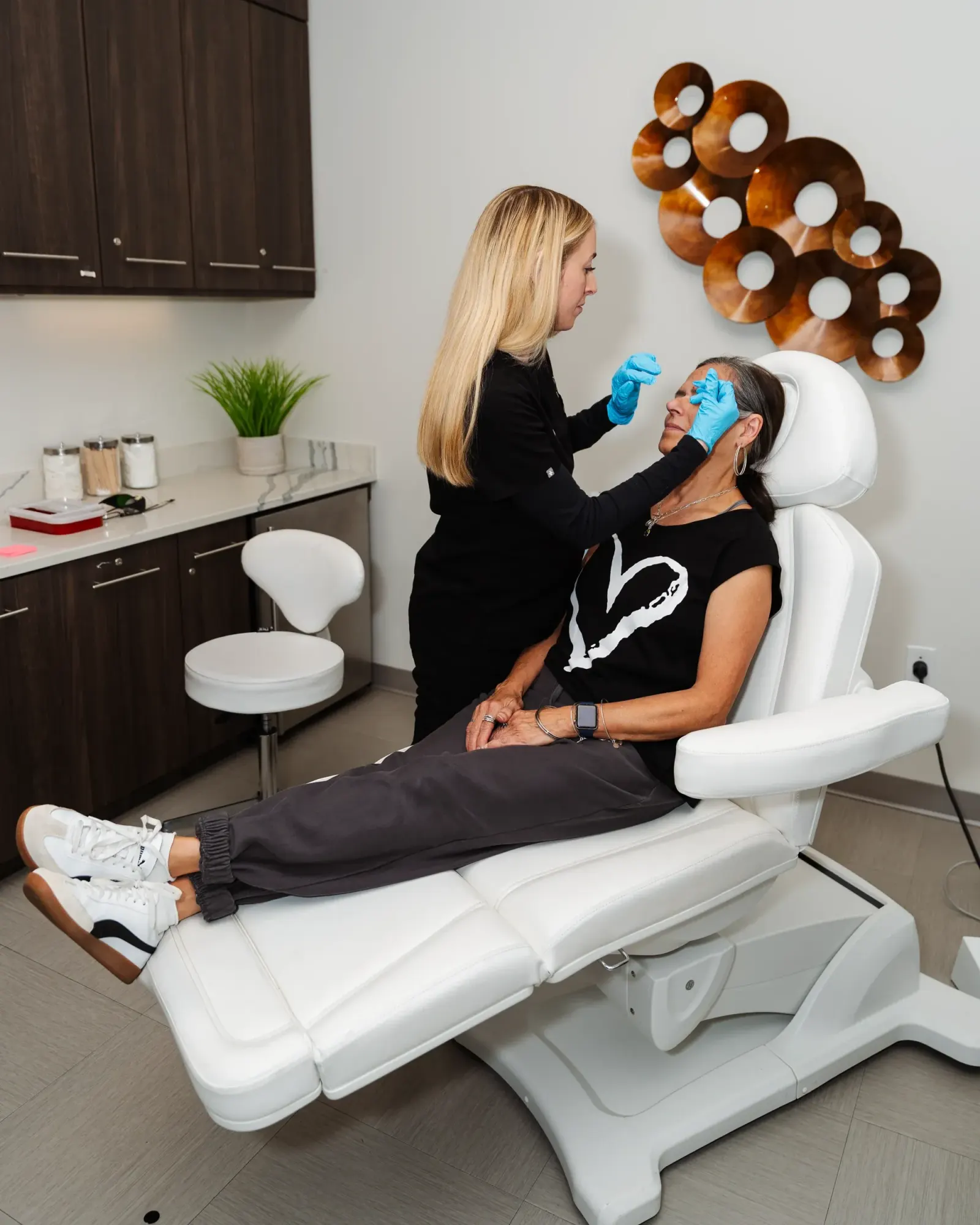 Provider preparing a reclined patient's face for treatment in a treatment chair