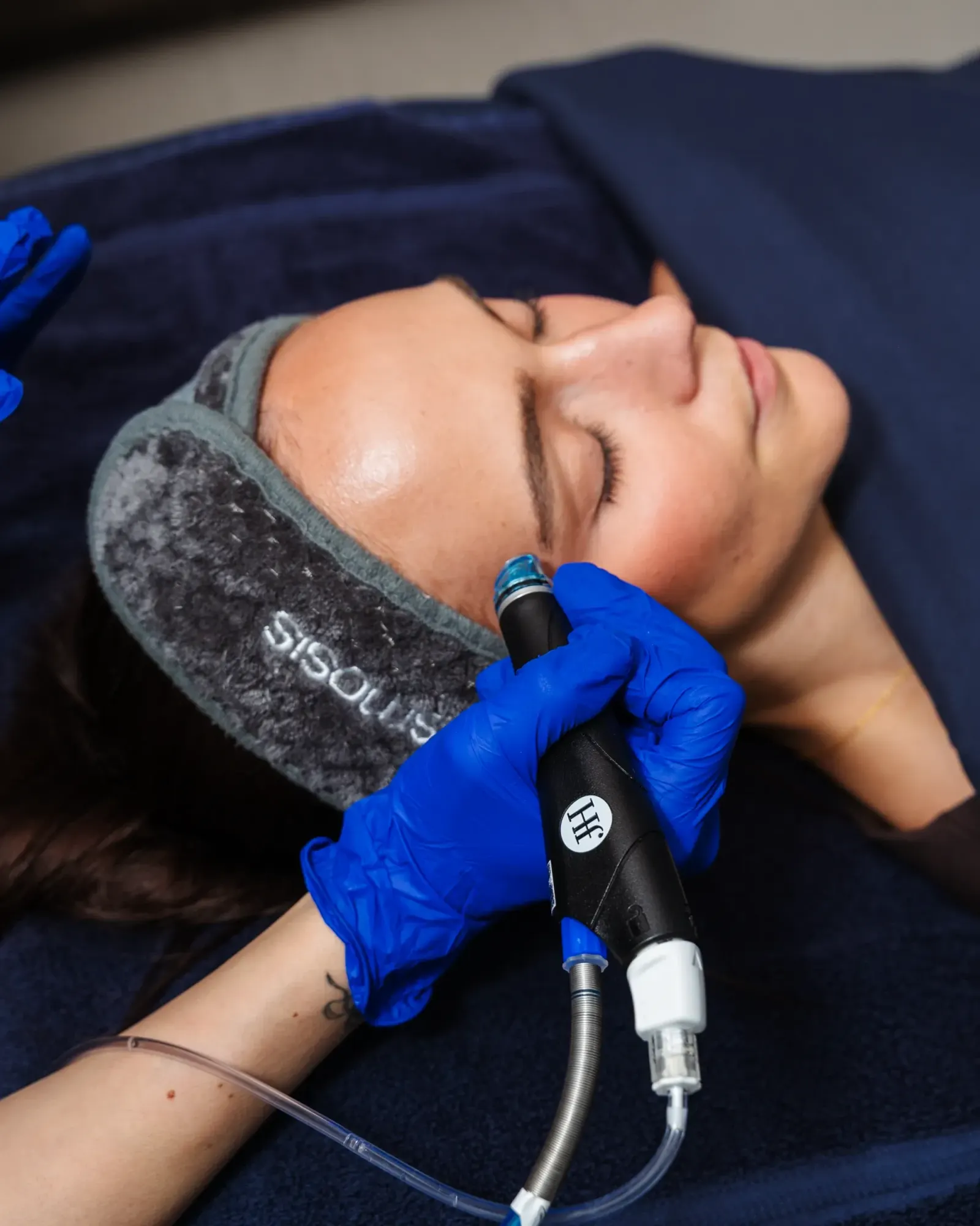 Reclined woman receiving a facial treatment with a handheld device on her cheek