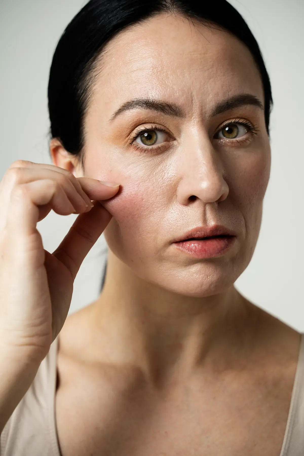 Woman examining her skin by gently pinching her cheek