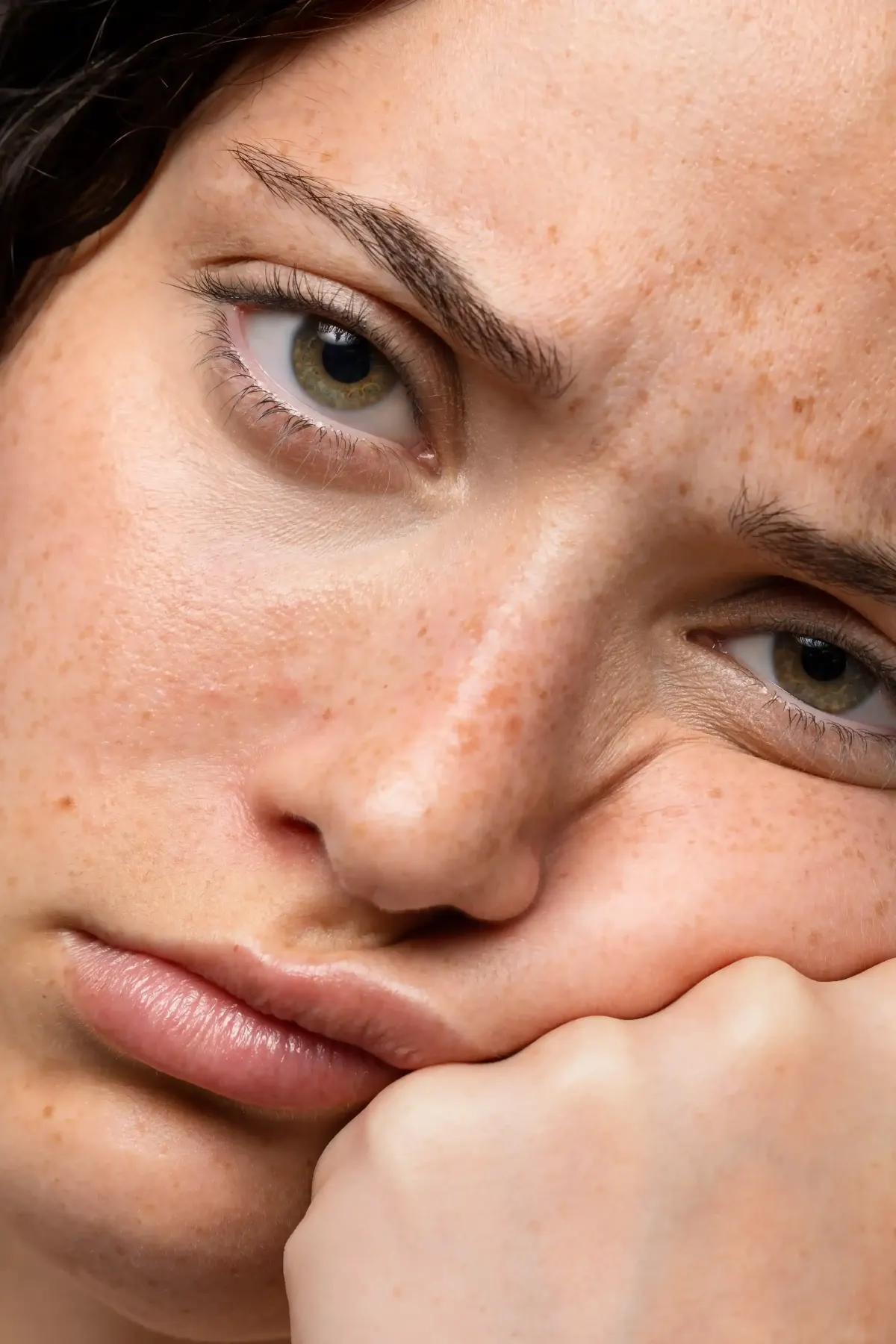Close-up of young woman's face showing freckles and visible pores