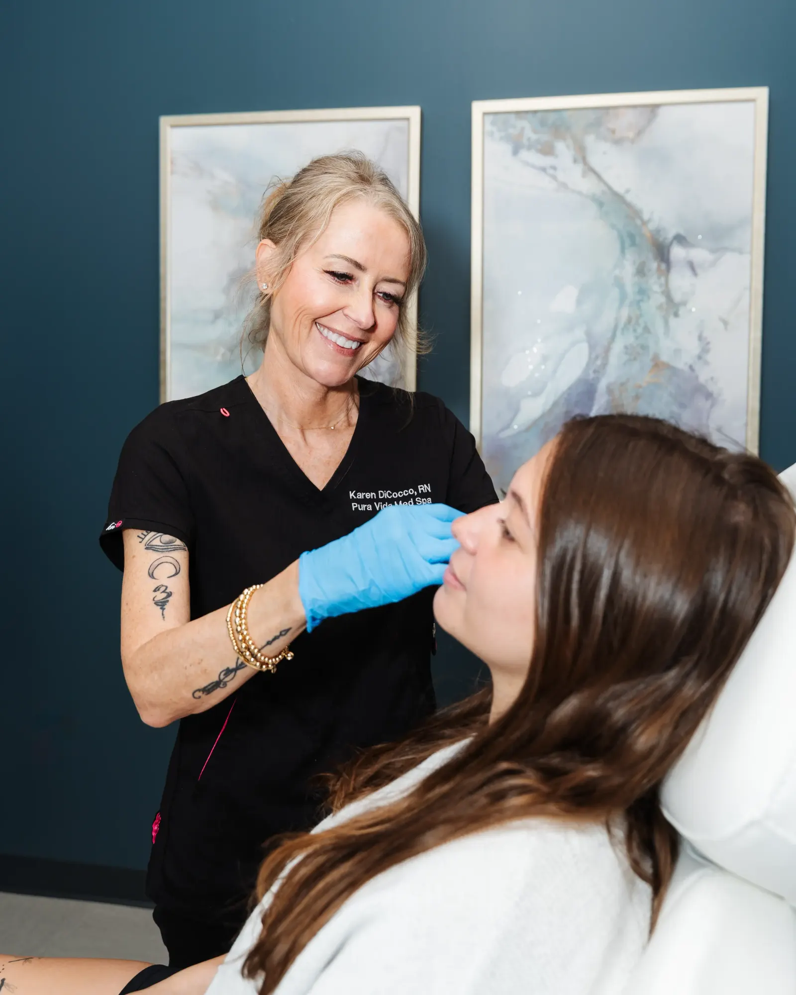 Provider in blue gloves treating a young woman's face during an injectable session