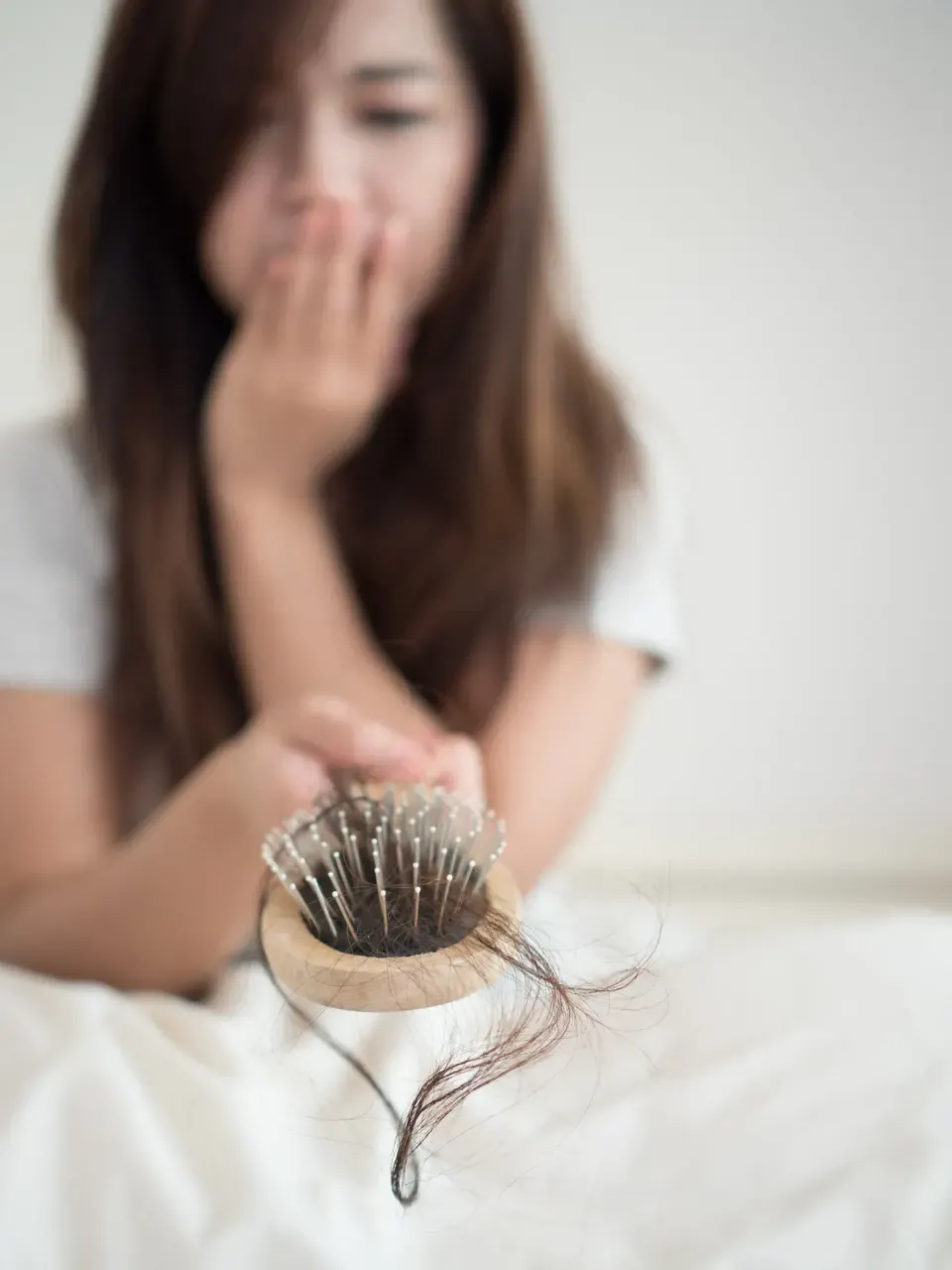 Concerned woman holding a hairbrush filled with fallen strands of hair