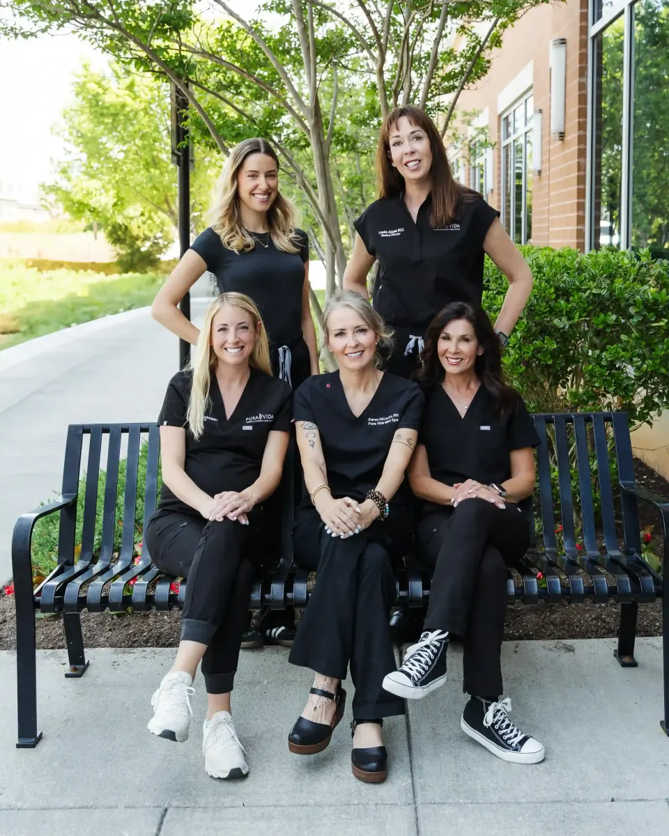 Pura Vida team of five staff in black uniforms posing on a sidewalk
