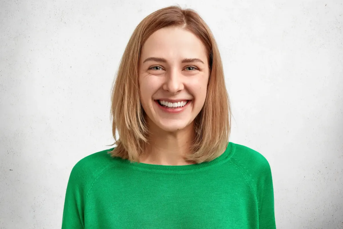 Cheerful young woman with bobbed hair and healthy skin in a green sweater