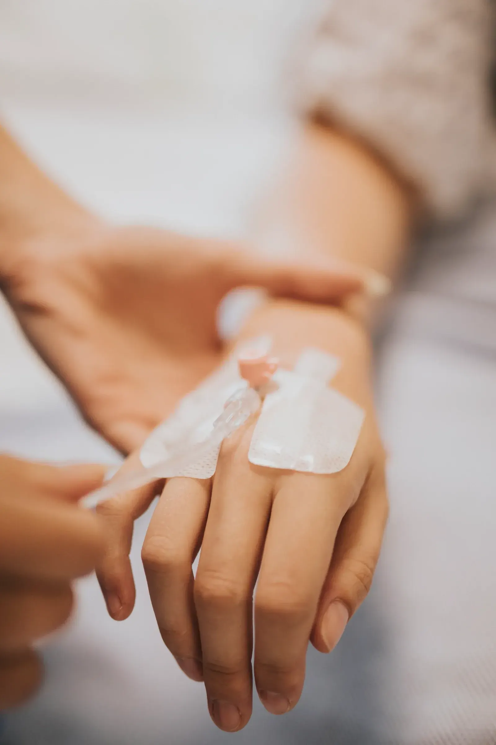 Close-up of a nurse securing an IV drip on a patient's hand