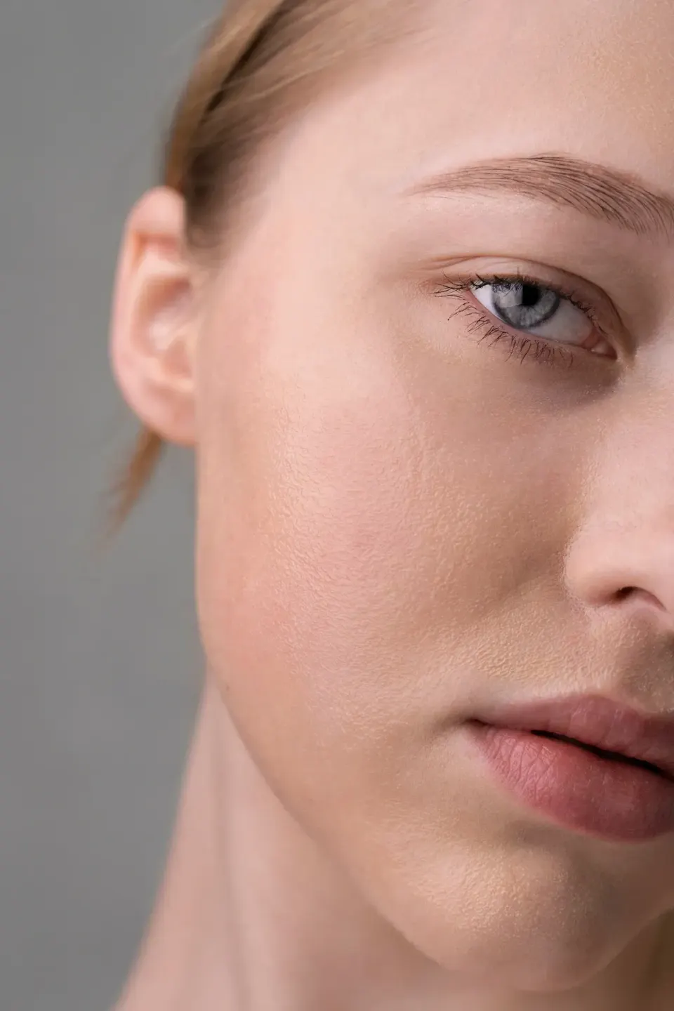 Half-face close-up of a young woman showing smooth cheek skin texture