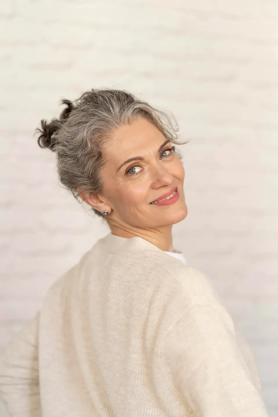 Smiling mature woman with gray hair looking over her shoulder