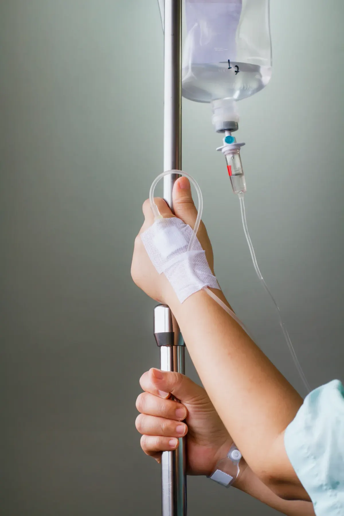 Patient's bandaged hand receiving a saline IV drip from a stand